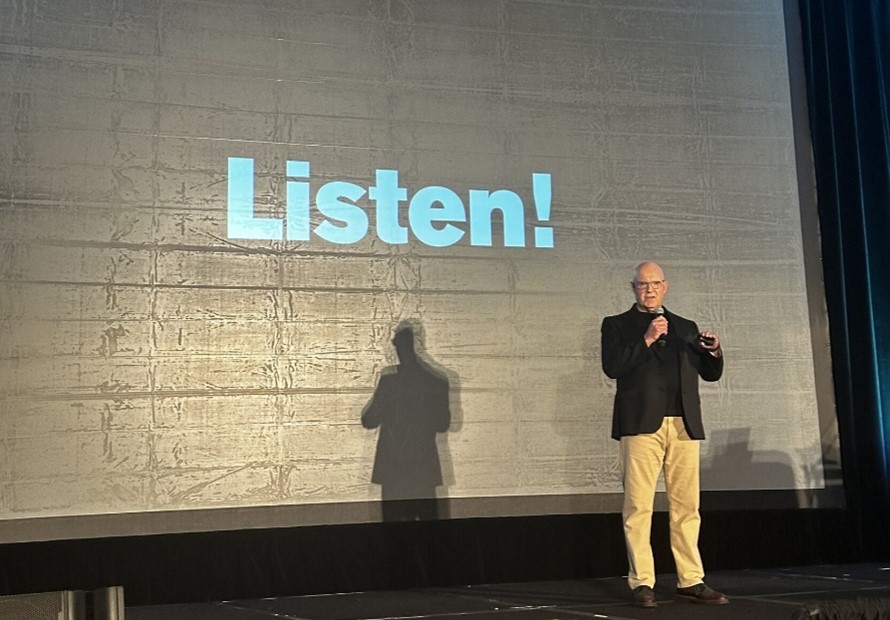 Julian Treasure on stage at IABC World Conference. Behind him a screen that reads, Listen!